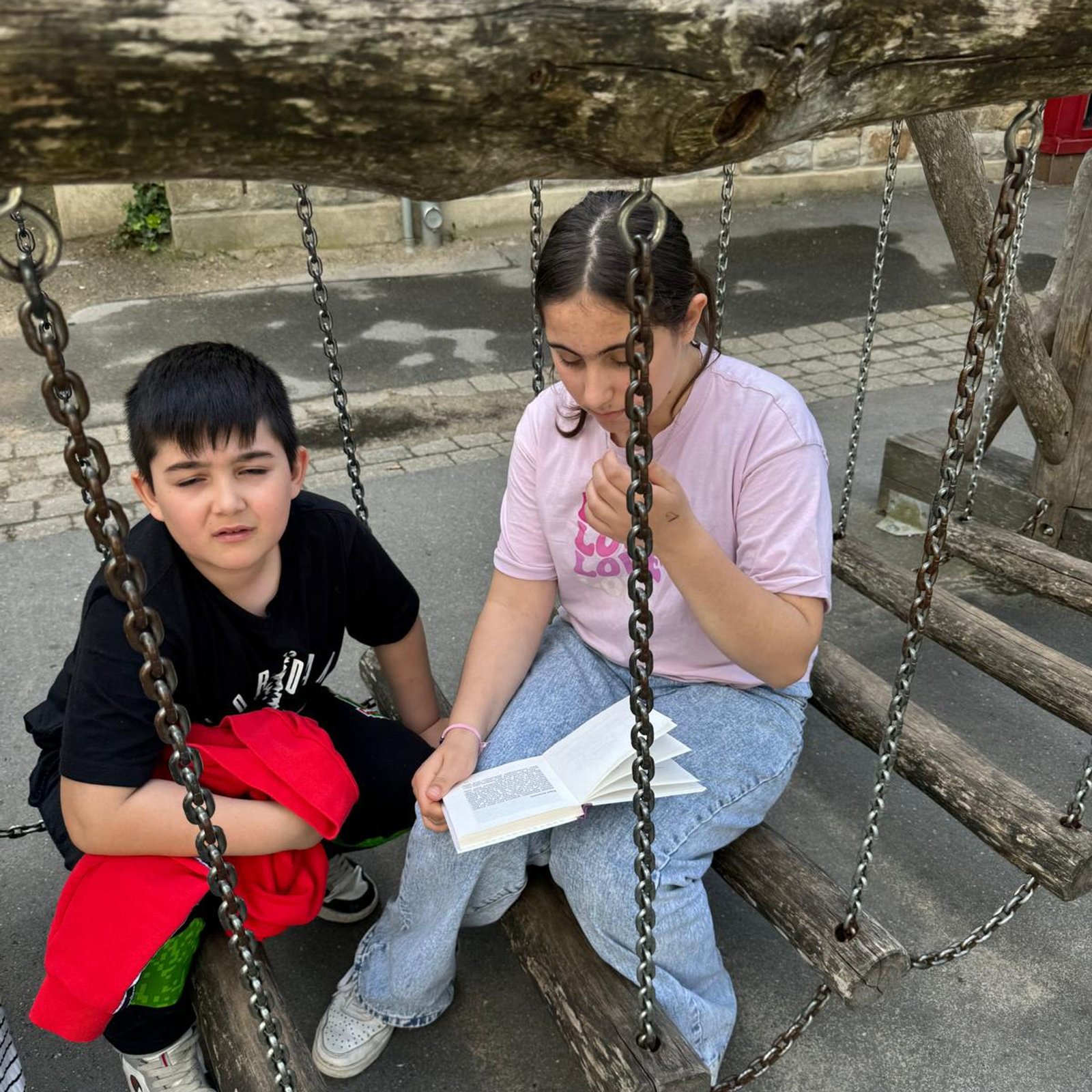 Kinder auf Schaukel mit Buch